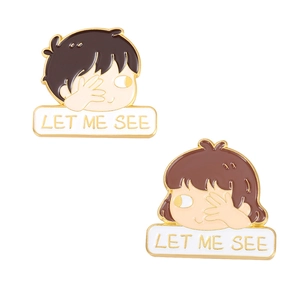 Detail of cartoon couple enamel pins with LET ME SEE text on white background