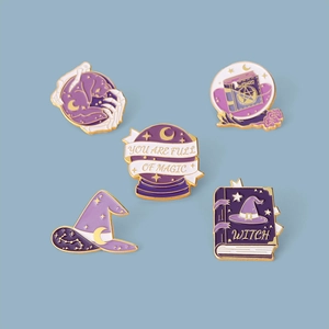 Close-up of five enamel magic brooches including wizard hat and crystal ball pins