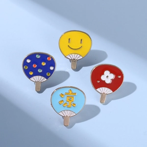 Gros plan de quatre pin's émaillés en forme d'éventail japonais avec motifs d'été colorés