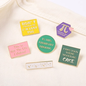 Detailed view of six colorful enamel science pins with gold trim on textured fabric