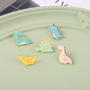 Set mit fünf bunten Dinosaurier Emaille Pins in einer grünen Keramikschale