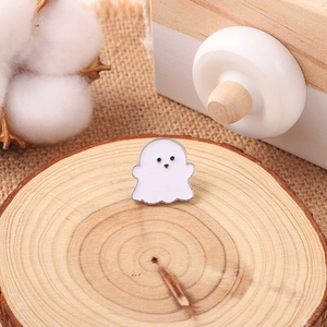 Cute white ghost enamel brooch with heart detail on a rustic wooden slice background