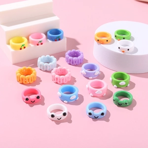 Détail de bagues colorées en résine avec motifs mignons de grenouille et de cerise