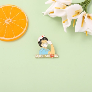 Detail of enamel pin showing a nurse with mask and Nurse Strong text on mint background