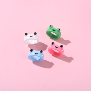 Vue à plat de quatre bagues grenouille mignonnes en résine blanc, vert, bleu et rose