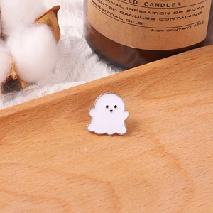 Macro detail of cute white ghost enamel pin with silver metal edges on wooden base