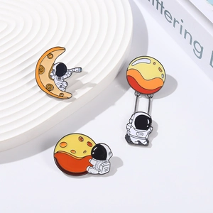 Trois pin's émaillés d'astronautes sur des lunes et planètes sur un support blanc