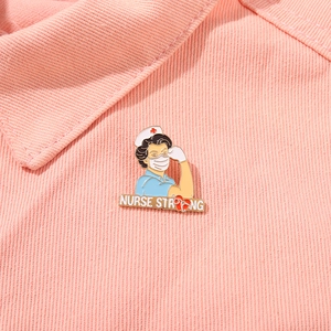 Macro detail of Nurse Strong enamel brooch pin on textured pink denim fabric background