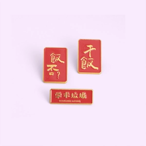 Detailed macro view of three red enamel pins with gold metal outlines and funny text