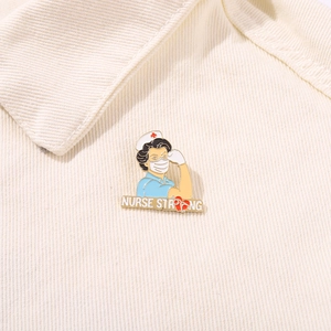 Close-up of golden enamel Nurse Strong brooch pinned on beige corduroy fabric texture