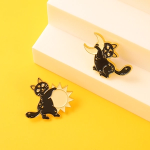 Set of two celestial enamel cat pins featuring sun and moon designs on yellow background