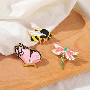 Détails des épinglettes en émail abeille, papillon et libellule sur plateau bois