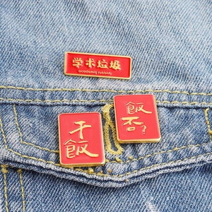 Detail of red enamel pins with funny academic and food text on blue denim fabric