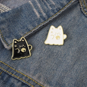 Gros plan détaillé des pin's mignons en émail de chat fantôme noir et blanc sur denim