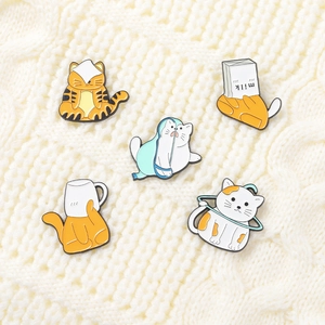 Détail d'un lot de cinq pin's en émail chat cartoon sur un fond de texture tricotée blanche