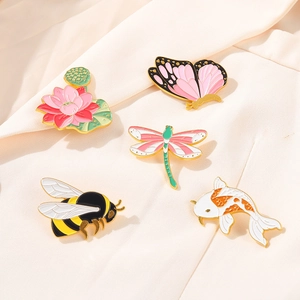 Détail des broches en émail avec lotus, papillon, abeille et carpe koï sur tissu