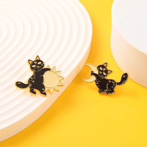 Enamel black cat brooches with gold sun and moon motifs on a yellow background