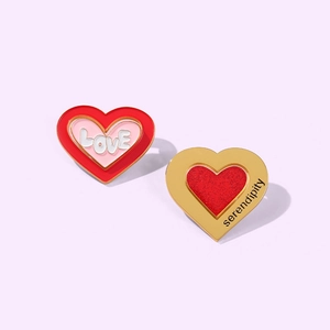 Detail of pink heart enamel pins with LOVE and serendipity text on lilac background