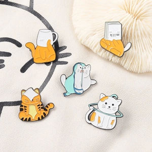 Détail de cinq épingles à chat mignonnes en émail orange et blanc sur toile