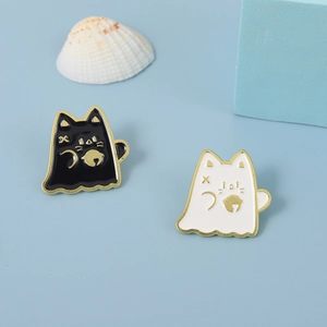 Gros plan d'épinglettes en émail chat fantôme noir et blanc avec détails dorés