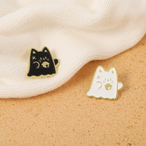 Gros plan d'épingles en émail chat fantôme noir et blanc sur un pull en tricot texturé