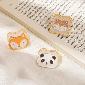 Détail de broches en émail panda et renard sur un fond de tissu blanc esthétique