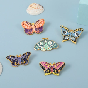 Detail of five butterfly and moth enamel pins with celestial moon and star elements