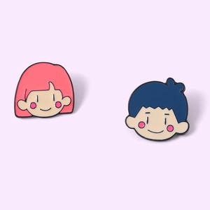 Détail des pin's émaillés fille rose et garçon bleu avec des motifs de dessins animés mignons