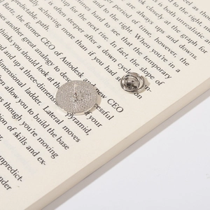 Silver metal brooch back accessory showing needle and butterfly clutch on a book