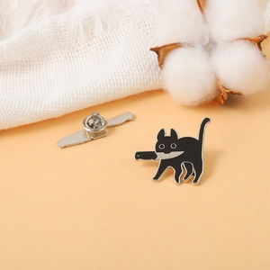 Black cat with dagger enamel pin badge on warm background with knit fabric and cotton decor