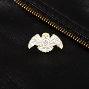 Detail of a white owl enamel brooch with gold metallic edges on black leather