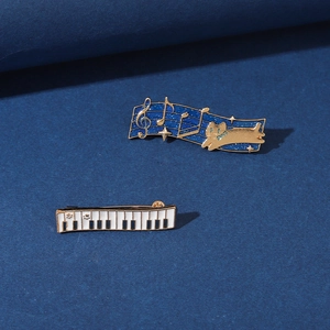 Detail of music enamel pins featuring a black piano and blue musical note cat design