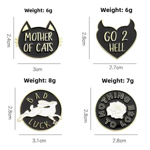 Detailed macro view of four black enamel pins featuring cat, rabbit and rose motifs