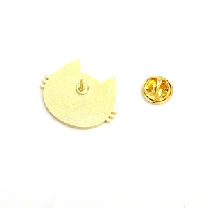 Macro detail of golden cat-shaped enamel pin back with frosted metal texture and butterfly clutch
