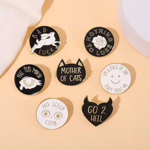 Detailed set of seven black and white enamel pins with gold edges on a neutral background
