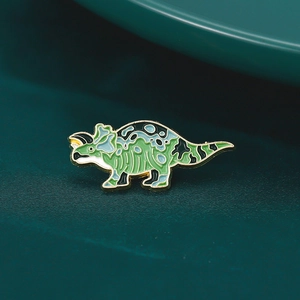 Détail d'une broche en émail dinosaure triceratops aux couleurs bleu vert et doré