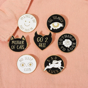 Detail view of 7 creative enamel pins including black cat and rabbit on pink fabric