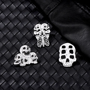 Detailed close-up of three punk style skull enamel pins on black leather texture