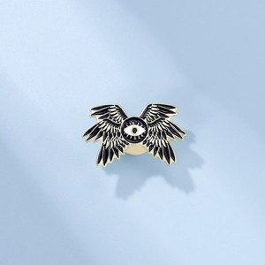 Gothic punk style enamel brooch with mysterious eye and black wings on blue background