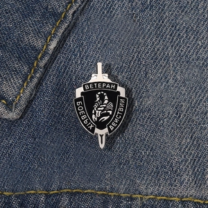 Détail d'un badge de vétéran scorpion noir et blanc épinglé sur un tissu en denim bleu