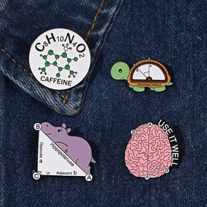 Close-up of four science-themed enamel pins with math and caffeine formulas on blue denim