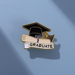 Detailed view of graduation lapel pin with black mortarboard hat and scroll design