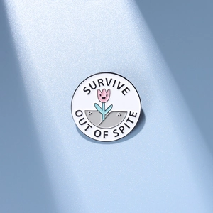 Détail de la broche ronde en émail avec motif floral et texte Survive Out Of Spite
