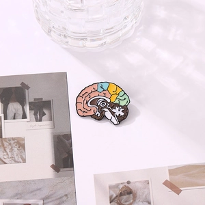 Macro shot of colorful anatomical brain enamel pin on a white card with elegant light shadows