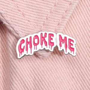 Detail of pink drip-style Choke Me enamel pin on a textured denim fabric background