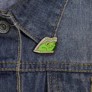 Creative frog in bread enamel pin with 'Let's Get This Bread' text on denim jacket