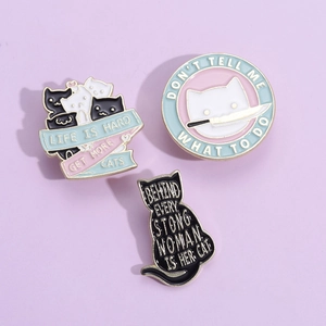 Détail de trois broches en émail chat créatives avec citations sur fond violet