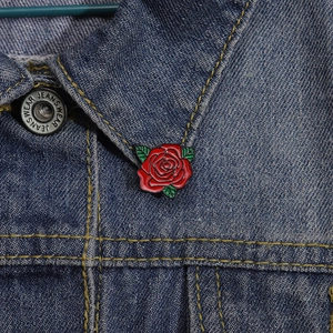 Cartoon red rose metal brooch pinned on blue denim jacket lapel as a creative gift