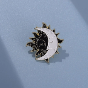 Detail of sun and moon enamel brooch with celestial face design and golden outlines