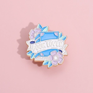 Macro detail of enamel book brooch with purple flowers and 'BOOK LOVER' text